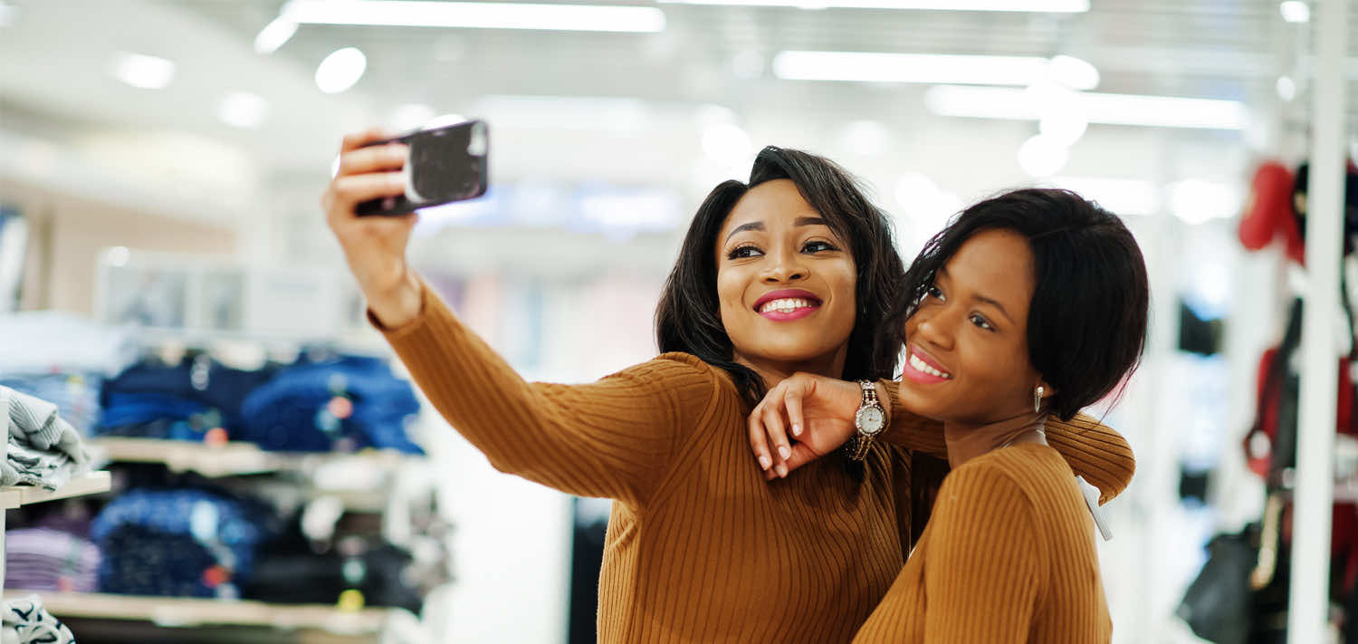 Smiling Young Woman Taking Selfie While Shopping